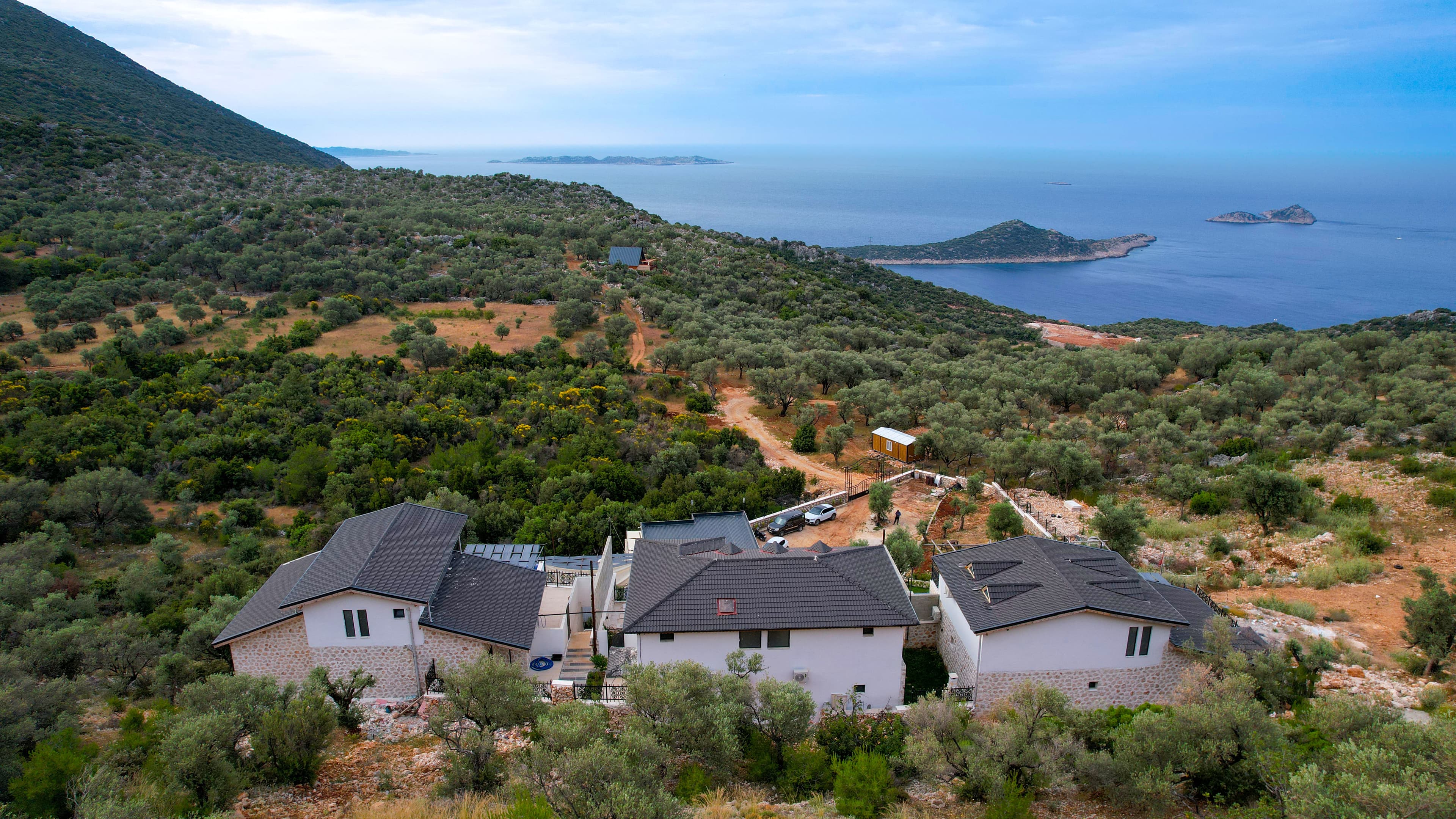 Aerial view of the five villas together on the hillside above Kalkan, each with its own pool and sea view