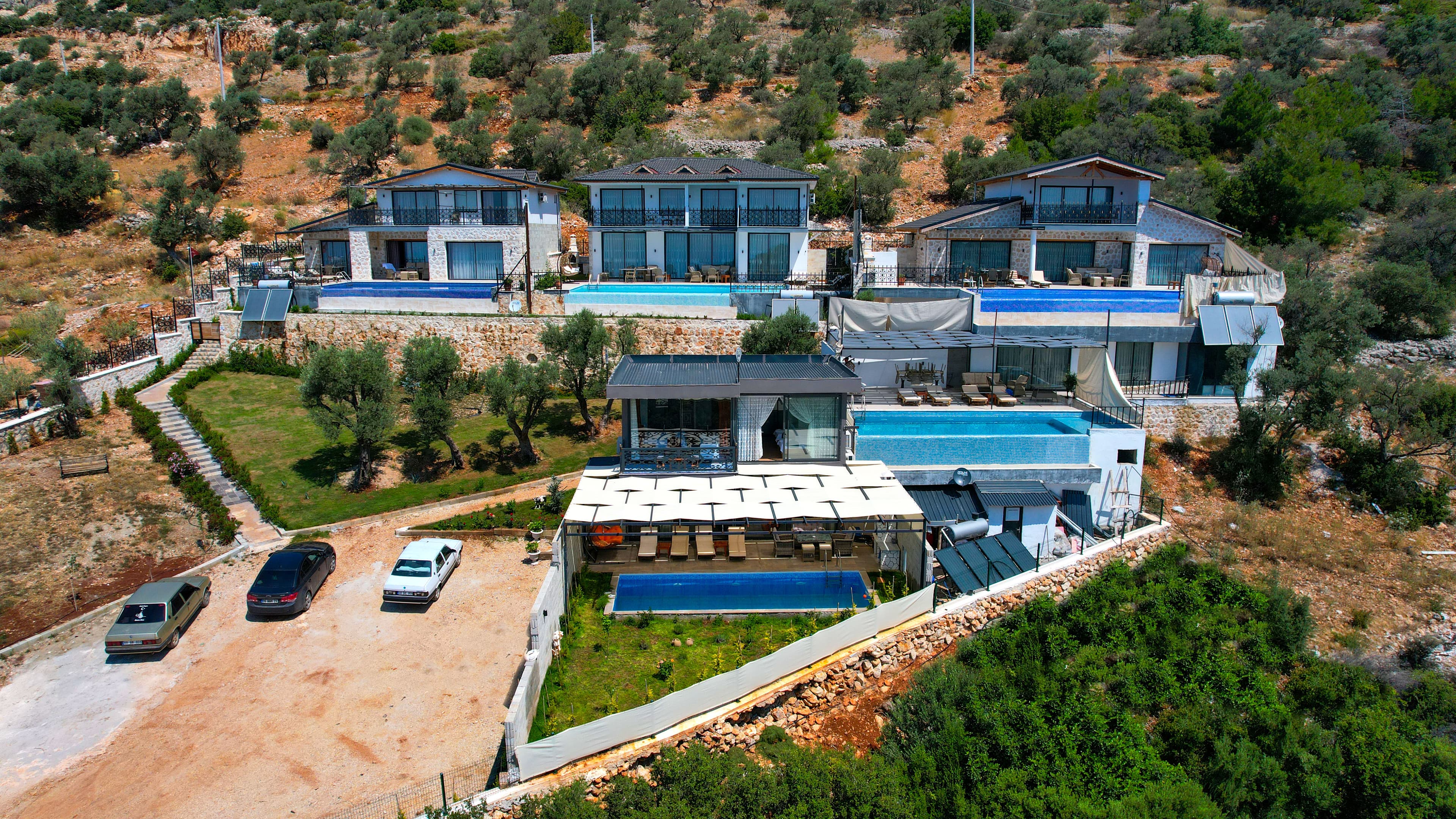 Aerial view of the five villas together on the hillside above Kalkan, each with its own pool and sea view
